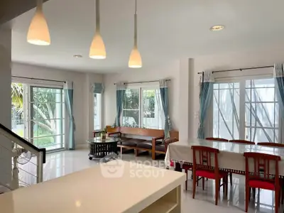 Spacious living and dining area with modern lighting and large windows.