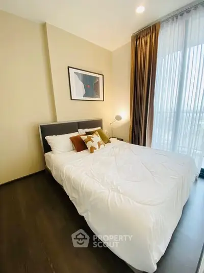 Cozy bedroom with modern decor and large window for natural light.