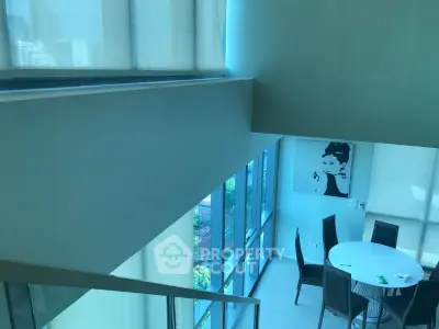 Modern duplex interior with high ceilings and large windows offering abundant natural light and stylish decor.