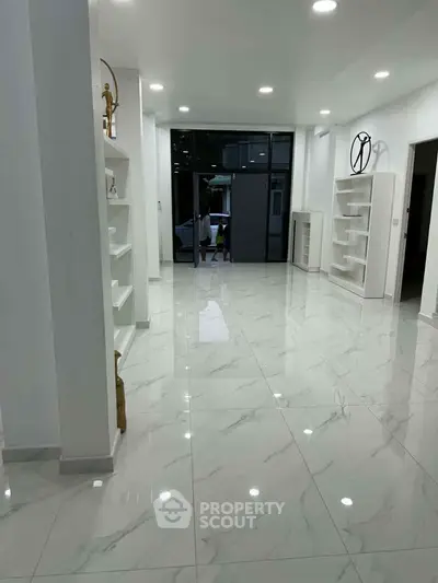 Spacious modern living room with glossy marble floors and elegant built-in shelves.
