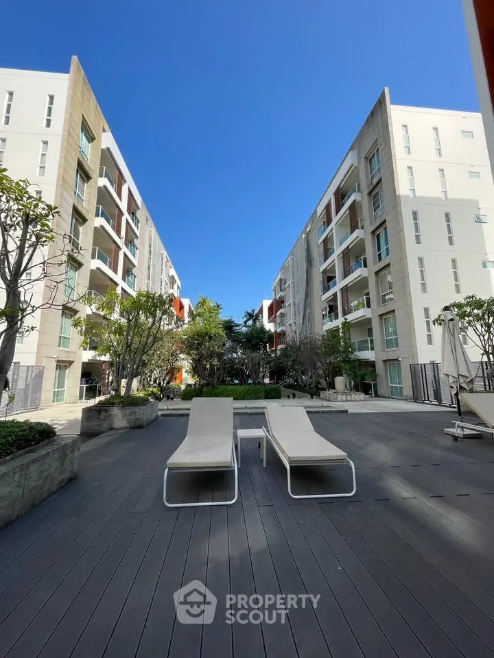 Modern apartment complex with spacious outdoor lounging area and lush greenery.