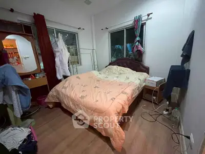 Cozy bedroom with wooden flooring and large windows for natural light.