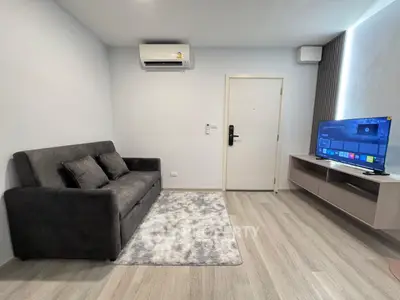 Modern living room with sleek sofa, wall-mounted TV, and air conditioning unit.