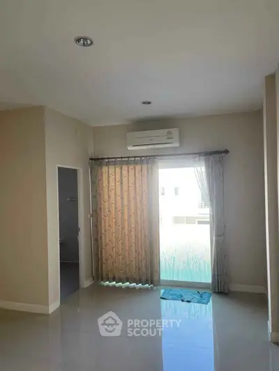 Spacious room with large window and air conditioning in modern apartment.