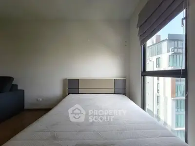 Spacious bedroom with large window and modern furniture in urban apartment