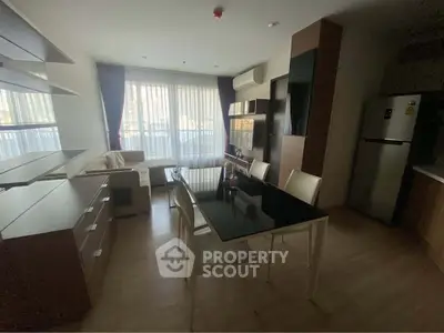 Modern living room with dining area and natural light, featuring sleek furniture and large windows.