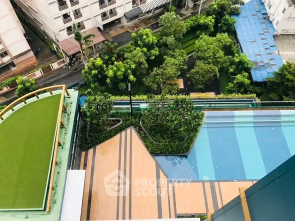 Stunning aerial view of modern building with lush garden and pool area.
