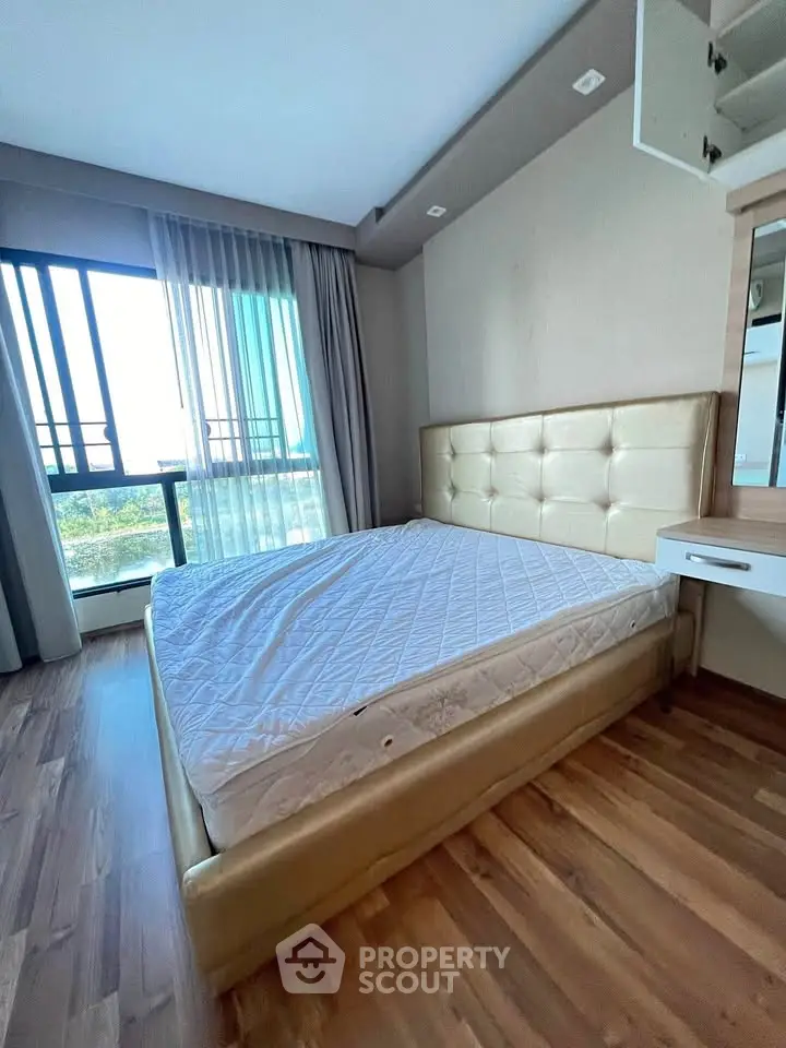 Spacious bedroom with large window and modern furnishings