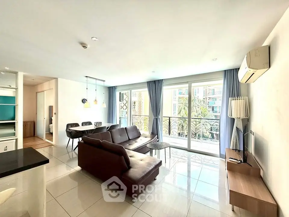 Spacious living room with modern furniture and large windows offering natural light and balcony access.