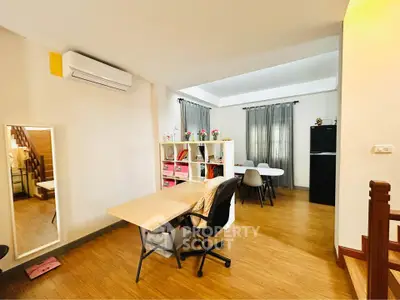 Spacious modern living area with study desk and dining table, featuring wooden flooring and natural light.