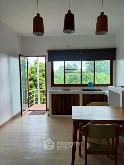 Bright kitchen with open layout and scenic view, featuring modern lighting and wooden accents.