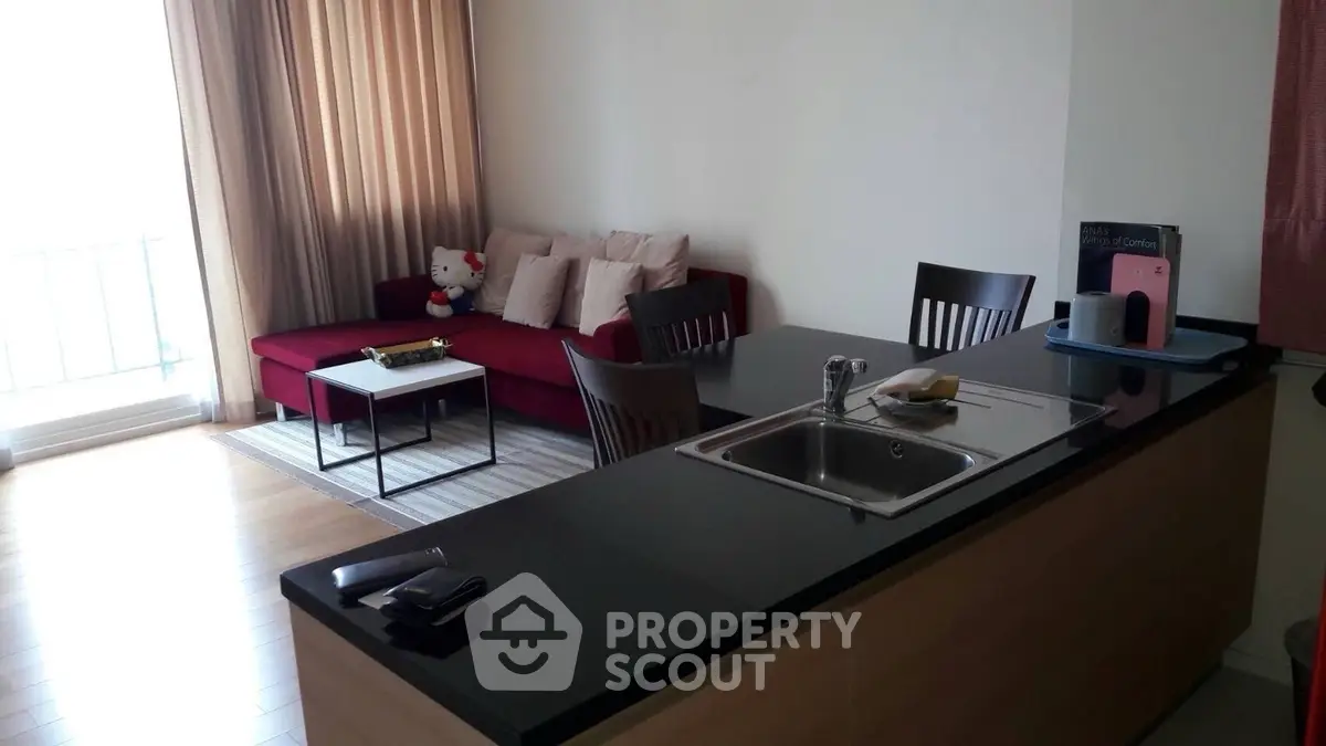 Modern open-layout living room with sleek kitchen island and cozy red sofa.