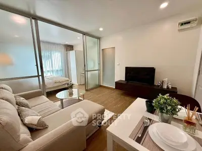 Modern living room with cozy sofa and TV, open to a bright bedroom