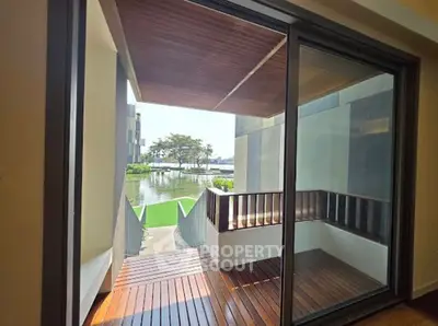 Stunning balcony view with wooden deck overlooking serene water and lush greenery.