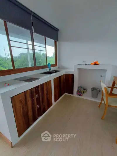 Modern kitchen with wooden cabinets and large window offering scenic views.