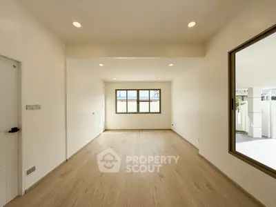 Spacious unfurnished room with large windows and wooden flooring, perfect for customization.