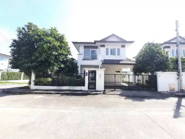 Charming two-story house with lush greenery and gated entrance in a serene neighborhood.
