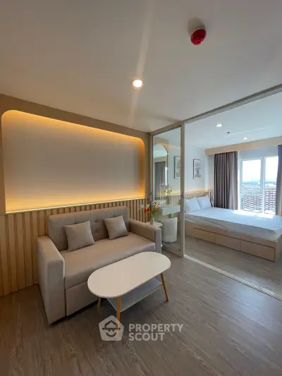 Modern open-plan living room with cozy sofa and elegant bedroom view