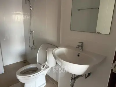Modern bathroom with sleek fixtures and white tiles, featuring a shower and toilet.