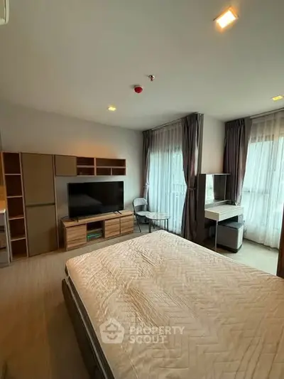 Spacious bedroom with modern furnishings and large windows for natural light.