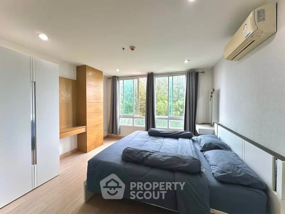Spacious bedroom with large windows and modern furnishings in a serene setting.