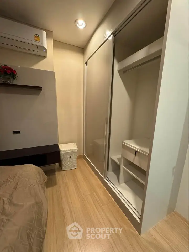 Modern bedroom with built-in closet and air conditioning, featuring sleek wooden flooring and ambient lighting.
