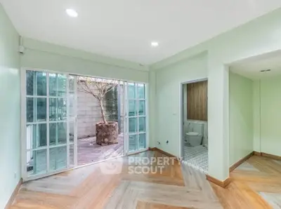 Spacious living room with sliding glass doors leading to a private patio, featuring modern flooring and ample natural light.
