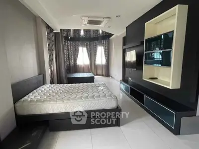 Spacious modern bedroom with sleek black furniture and large windows.