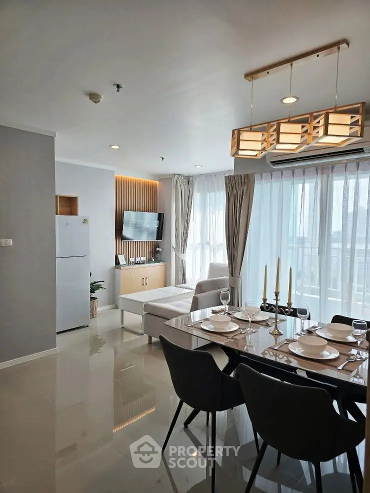Modern living room with dining area, sleek furniture, and large windows offering natural light.