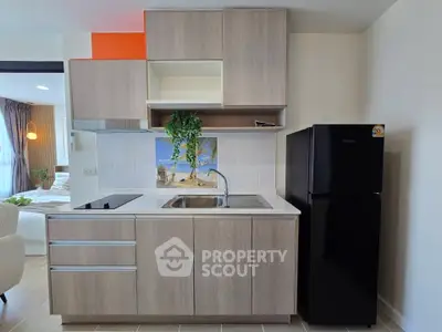 Modern kitchen with sleek cabinetry and black fridge in a stylish apartment.