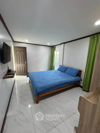 Spacious bedroom with modern decor and natural light, featuring a comfortable bed and sleek flooring.