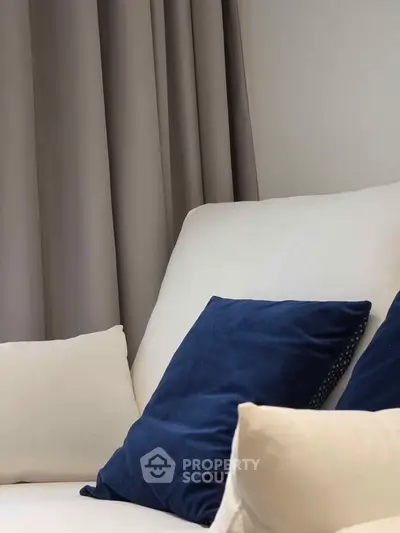 Cozy living room corner with elegant white sofa and plush blue cushions, perfect for relaxation.