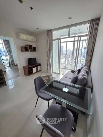 Modern living room with city view, glass dining table, and cozy sofa in a high-rise apartment.