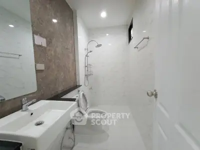 Modern bathroom with sleek fixtures and marble accents, featuring a spacious shower and elegant sink.