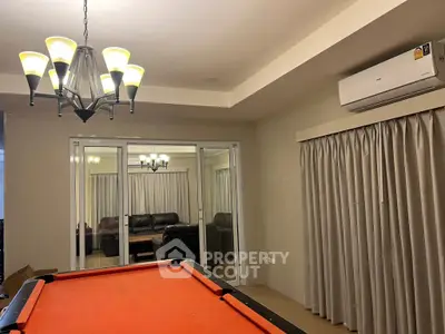 Spacious living area with pool table and modern lighting, perfect for entertainment.