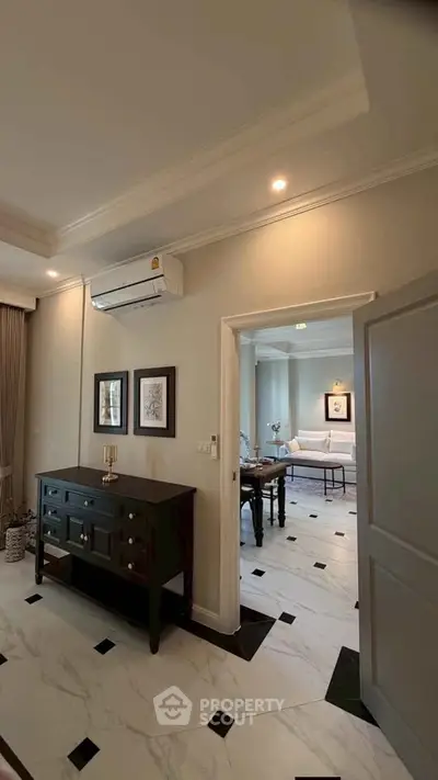 Elegant living room with stylish decor and marble flooring, featuring a cozy seating area and modern air conditioning.