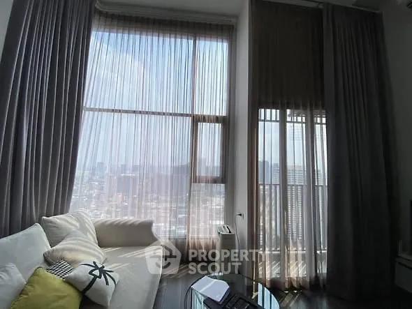Spacious living room with floor-to-ceiling windows offering stunning city views and elegant decor.