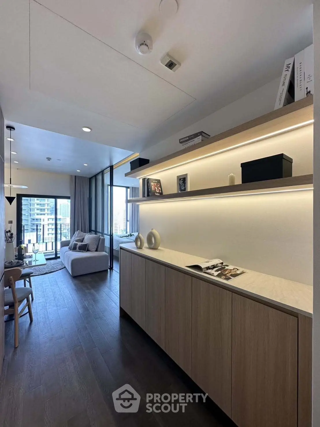 Modern living room with sleek wooden flooring and elegant shelving, offering a cozy urban view.