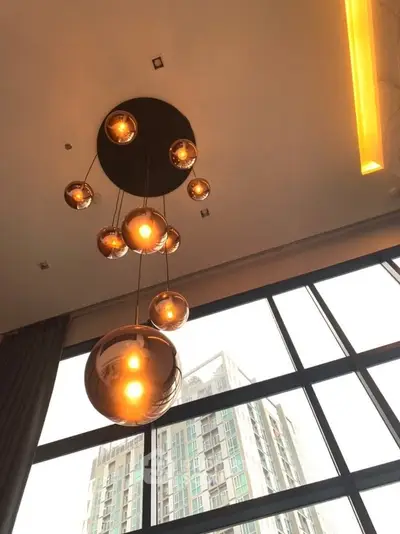 Modern high-rise apartment with elegant pendant lighting and large windows.