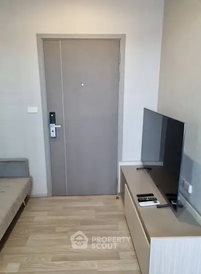 Modern apartment entrance with sleek door and flat-screen TV in cozy living area.