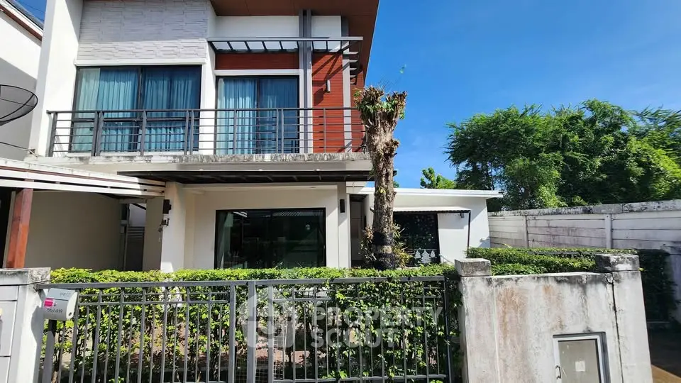 Modern two-story house with large windows and lush greenery