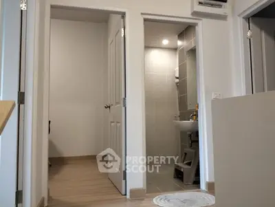 Modern apartment interior with bathroom and hallway view, showcasing sleek design and neutral tones.