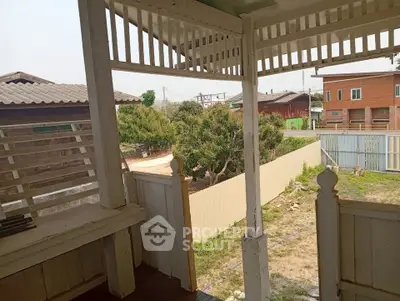 Charming rustic balcony with wooden railing overlooking a serene suburban neighborhood.