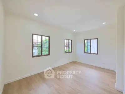 Spacious and bright room with large windows and wooden flooring, perfect for a modern living space.