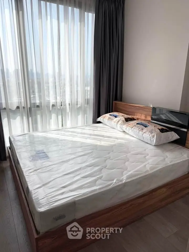 Modern bedroom with large window and wooden bed frame, offering a bright and inviting atmosphere.