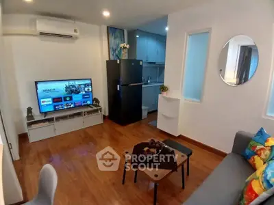 Modern living room with wooden flooring, stylish furniture, and a sleek kitchen area.