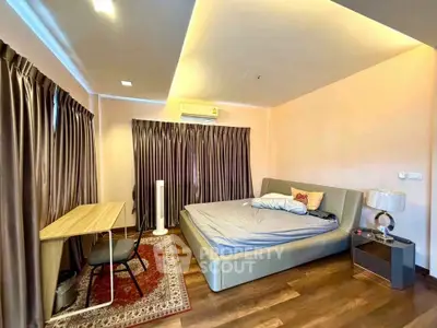Spacious bedroom with modern design, featuring a large bed, desk, and elegant lighting.
