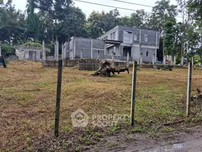 Unfinished residential building on a spacious plot surrounded by lush greenery, ideal for development.