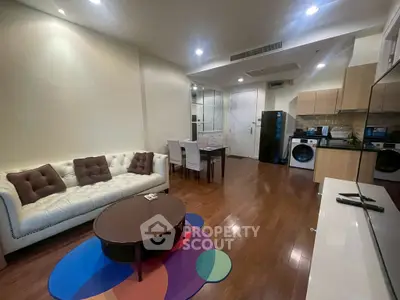 Spacious modern living room with open kitchen, featuring hardwood floors and stylish furniture.