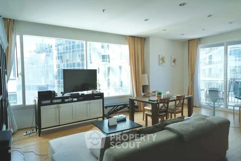Spacious living room with large windows and modern decor in a bright apartment.
